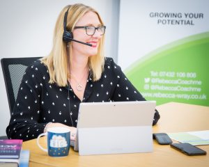 Image of Rebecca sat at laptop with headset ready to deliver virtual learning