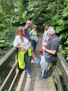 group of people paused on bridge reflecting on how the environment supports their thinking.  Another benefit of outdoor coaching as this photo shows a moment of connection and focus.